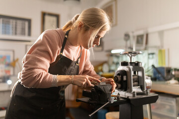 Woman artisan crafting metal in jewelry workshop