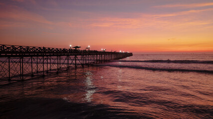 Fototapeta premium Panoramic aerial drone photo of a beautiful sunset over Pimentel, Chiclayo, northern Peru, a coastal tourism destination for travel and summer vacations