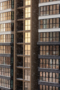 Metropolitan shopping complex with glowing windows surrounded by snow as day turns to night