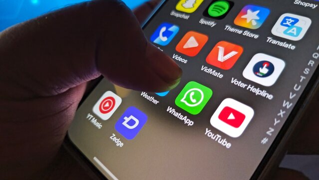 A hand interacting with a smartphone screen displaying various app icons