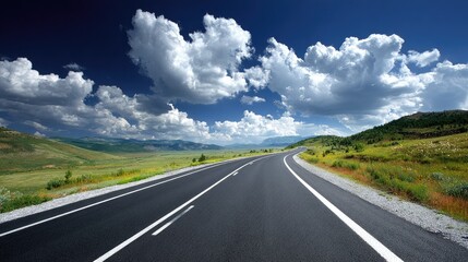 Smooth asphalt highway curves through rolling green landscape beneath dramatic sky