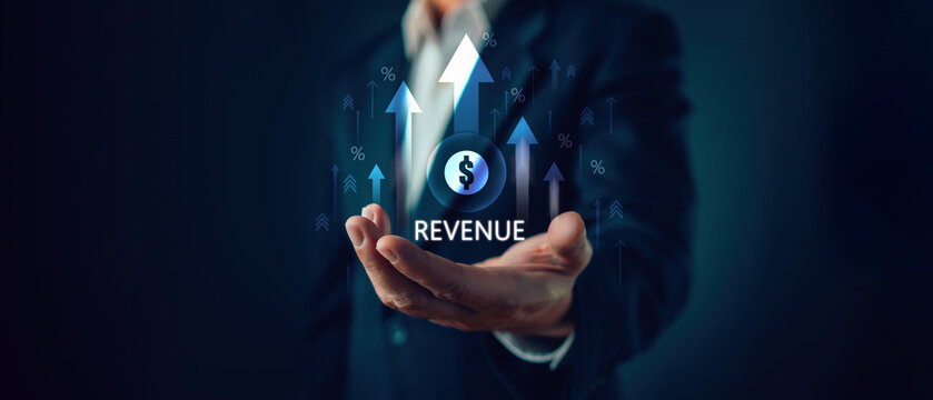 Businessman holding virtual revenue growth hologram with dollar sign and upward arrows. Financial profit increase concept for corporate sales success, economy investment and money income market.
