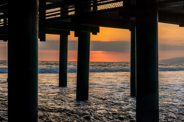 Sunset Waves Clash Against Pier on Glowing Horizon
