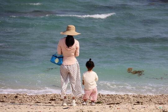 Woman with kid girl on sea beach. Young mom with little daughter, vacation concept