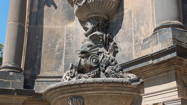 A decorative stone vase carved with sea creatures on the facade of a historic building.