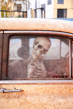 Skeleton sitting inside an old abandoned car