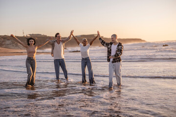 Fototapeta premium Diverse friends connecting celebrating freedom on beach at sunset