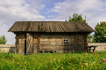 Obraz premium Authentic log cabin in a village setting, showcasing aged timber walls, wooden roof, and natural rural environment.