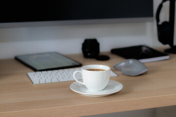 Cup of tea on programmer's desk with keyboard, tablet and monitor