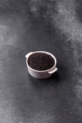 Black sesame seeds in a bowl, an ingredient for oil and healthy eating. Black sesame