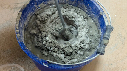 Naklejka premium Mixing concrete in a cerulean bucket, industrial alchemy, building dreams recipe, nod to Worker's Day festivities