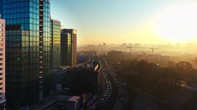 Sunrise drone cityscape modern urban skyline. Aerial morning view urban center highrise architecture glass buildings traffic street golden light haze atmosphere.