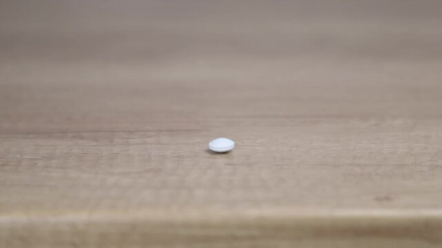 Close up of female hands taking white pill from a blister pack over a wooden table