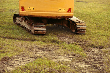 A large yellow hydraulic excavator parked on a grassy hillside. Undergoing construction or land modification. Preparing terrain for snowmaking infrastructure