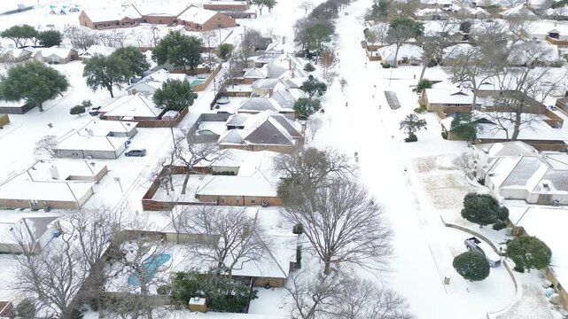 Mockingbird Elementary School campus shows snow-covered rooftops, playgrounds, and adjacent homes. Brick textures and blue canopy playground emerge thru Winter Storm Fern frosty, Coppell, Texas