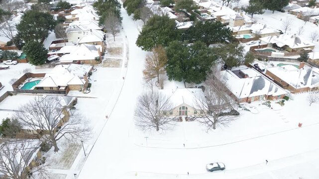 Homes near Mockingbird Lane and Falcon Lane in Northlake Woodlands subdivision show snow-covered rooftops, driveways, leafless trees. Pools, fences contrast under Winter Storm Fern, Coppell, TX