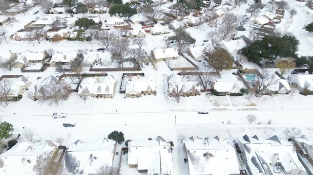 Residential zone Mockingbird Lane, Falcon Lane snow-covered rooftops, roads, scattered trees. Parked vehicles and curved street add subtle motion to Winter Storm Fern quiet canvas, Coppell, TX