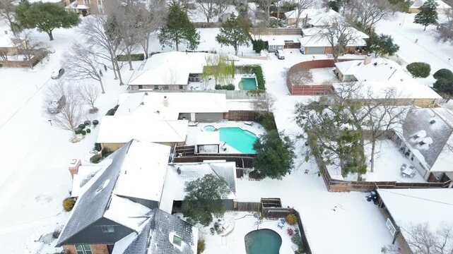 Northlake Woodlands homes west of Mockingbird Elementary School feature snow-draped roofs and visible backyard pools. Bare branches, soft shadows reflect Winter Storm Fern icy grip, Coppell, TX