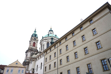 Low angle view of historic clock tower framed by arch and building facades, vertical urban corridor with classic architecture and time symbol under bright sky background.