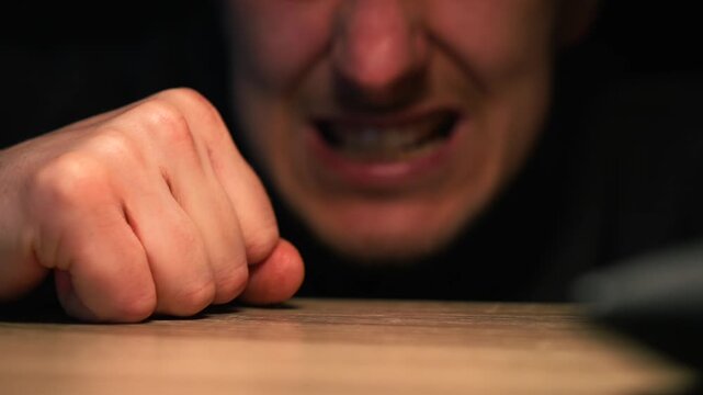 A man screams in rage and slams his hand on the table.
A man slams his fist on the table in anger.
Negative emotions and anger