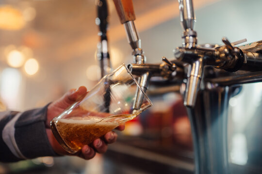 Bartender pouring draft beer from a tap at a bar