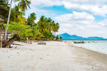 Koh Mook island, Kantang, Trang, Thailand, presenting a peaceful tropical beach with swaying palm trees, crystal clear water, and traditional longtail boats docked along the sandy shore © arkanto