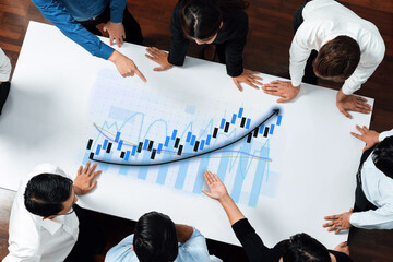 A diverse business team engaged in a collaborative discussion over financial graph analysis, visualizing data trends and strategies on a presentation sheet. Axiom