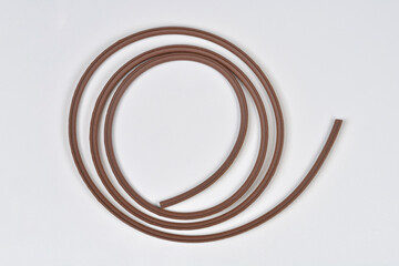 A brown adhesive foam strip for window sealing shown in a gentle curve on a clean white background with its yellow backing paper visible