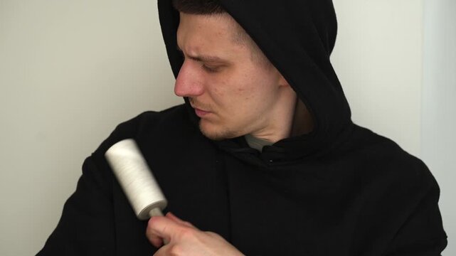 A man removes lint and lint from black clothing with a lint roller.
Cleaning clothes with a lint roller.