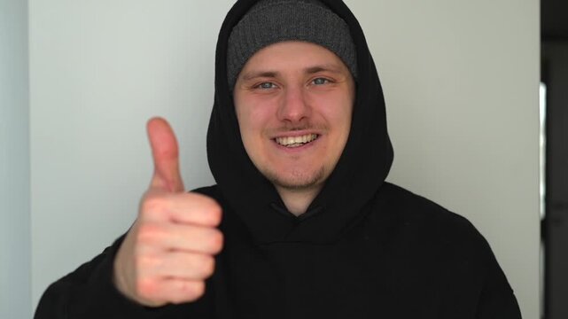 A man in a hoodie makes a thumbs-up gesture.
A gesture of approval and positivity.
Very good, super, delighted.