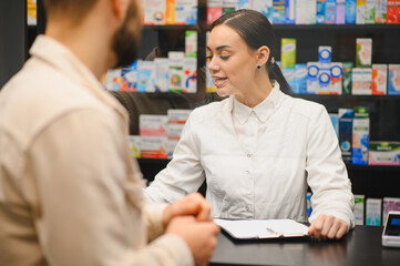 Pharmacist providing consultation to male customer in pharmacy