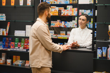 Pharmacist assisting customer at modern pharmacy counter