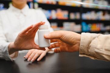 Pharmacist handing prescription medicine bottle to customer