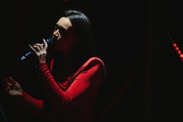 Female singer performing live on dark stage with microphone