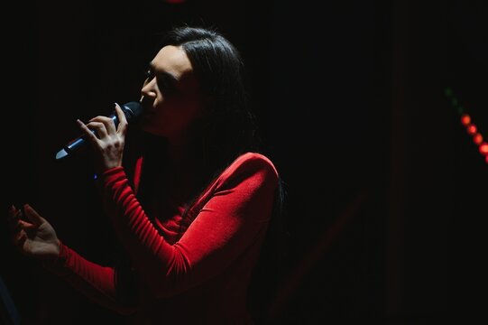 Female singer performing live on dark stage with microphone