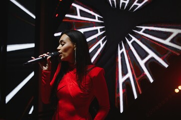 Female singer performing live music on stage with microphone