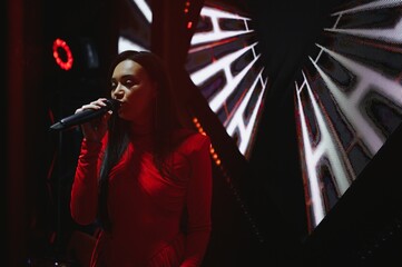 Female singer performing live with microphone in spotlight
