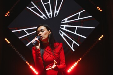 Singer performing live on stage with microphone and lights