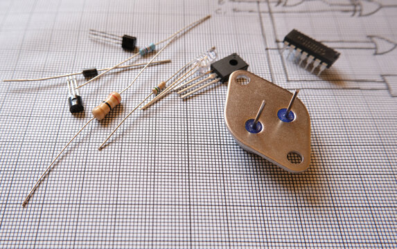 Electronic components on the desk with a circuit diagram. Focused on metal-cased transistor.