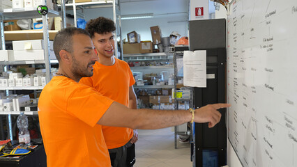 Collaborative shift planning meeting between workers in warehouse in front of planning board