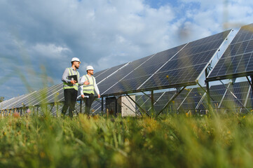 Obraz premium Engineers inspecting large solar power panels in field