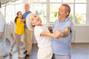 Fototapeta premium Couple of elderly man and elderly woman dancing waltz in studio