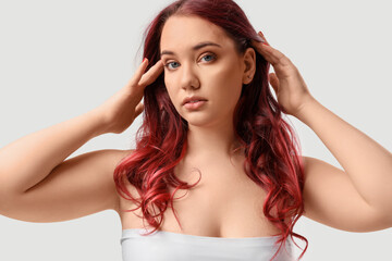 Fototapeta premium Beautiful young woman with curly red hair on white background