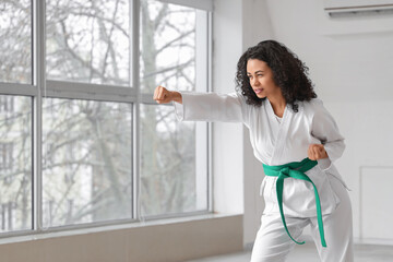 Young African-American woman with green belt practicing karate in dojo © Pixel-Shot