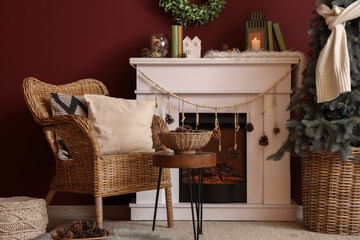 Naklejka premium Interior of living room with fireplace, wicker armchair, Christmas tree and coniferous cones