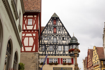 Fototapeta premium Market Square of Rothenburg ob der Tauber, Germany, with historic Town Hall Tower, Ratstrinkstube Clock Tower, half‑timbered houses, cobblestone streets, fountain and shops in medieval Bavarian town.