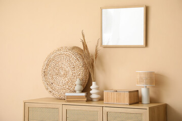 Interior of living room with chest of drawers near beige wall