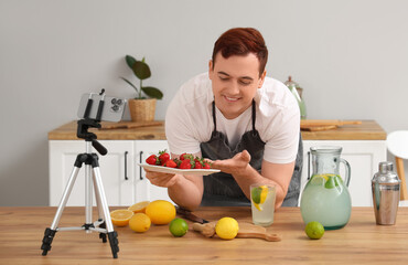 Fototapeta premium Young man recording video of him making homemade lemonade in kitchen