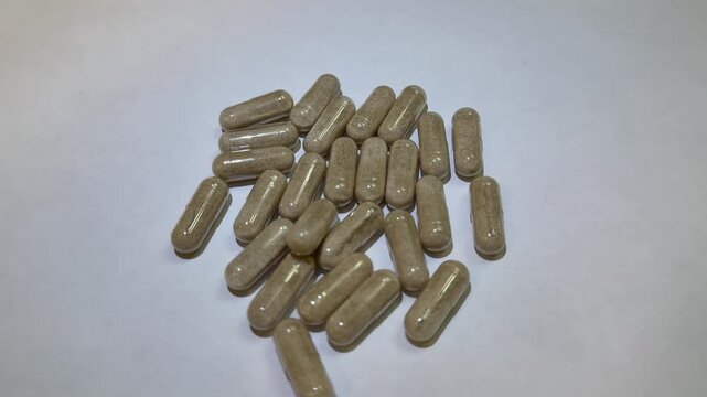 Caucasian woman sorting supplement capsules on white surface, closeup hand selecting herbal tablets from scattered pile, slow methodical motion, careful dosage planning, soft studio