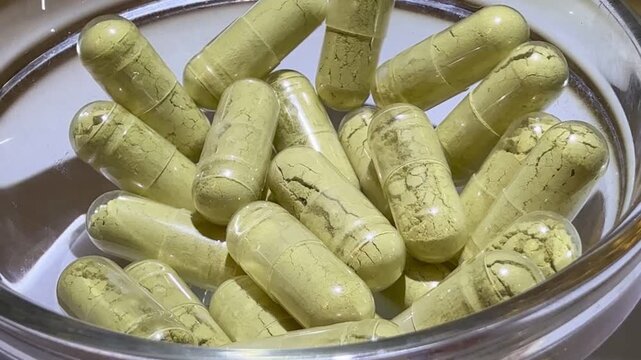 Close-up of woman's fingers counting capsules in glass jar, soft clinical lighting, beige herbal capsules with visible granules, careful fingertip movement, dosing routine and supplement